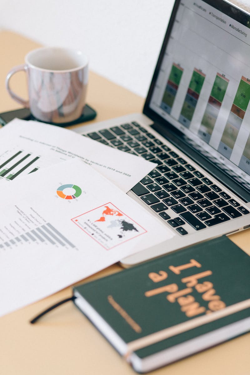 Close-up of a desk with a laptop, documents, and a coffee mug, ideal for business and office themes.